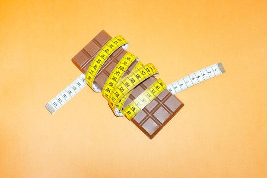A tape measure wraps around a chocolate bar