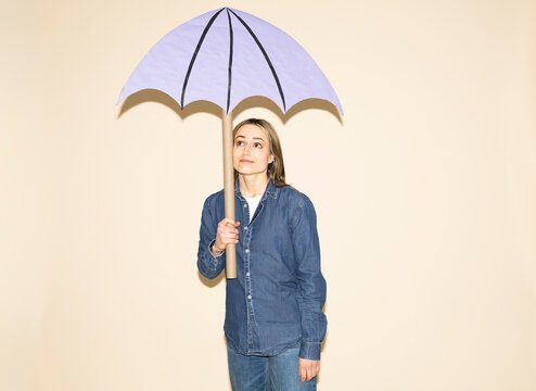 Woman holding a handmade purple paper umbrella in a denim outfit