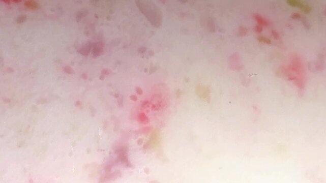 Macro extreme close up of blended fruit juice smoothie mixture with colorful jelly pieces and small air bubbles texture background
