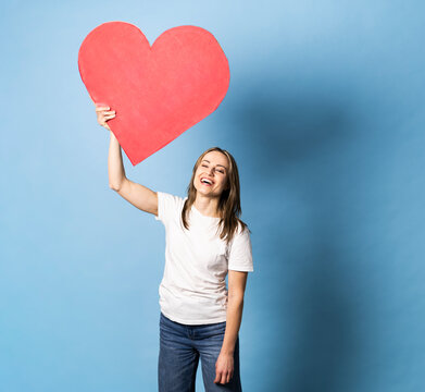 Smiling customer holding a red paper heart showing brand loyalty