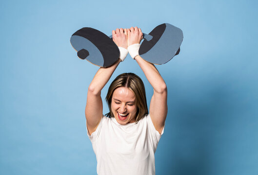 Woman lifting a fake paper dumbbell showing strength and effort