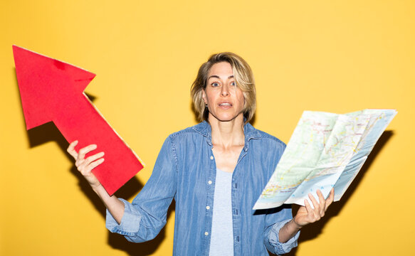 Confused woman holds a map and red arrow planning travel indoors