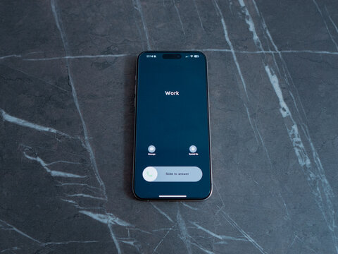 Smartphone displays an incoming call from work while resting on a table. The screen shows options to accept or decline the call in a clear view.