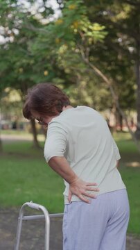 Senior Asian Woman Using Walker Frame Suffering from Severe Back Pain at Park