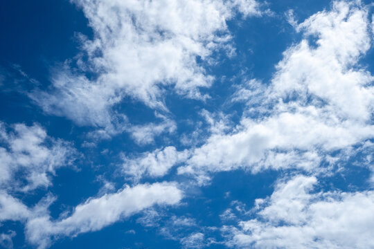 Blue sky with soft white clouds forming natural patterns in bright daylight, creating a peaceful atmospheric background for weather, nature, climate, freedom and environmental concepts.