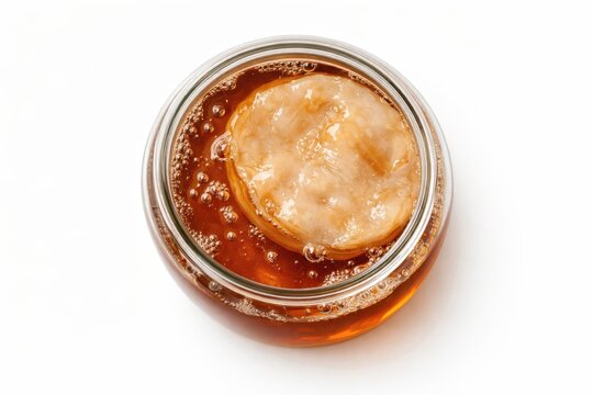 Top view of brewing kombucha tea in a glass jar with a fermentation scoby mushroom for natural organic drinks