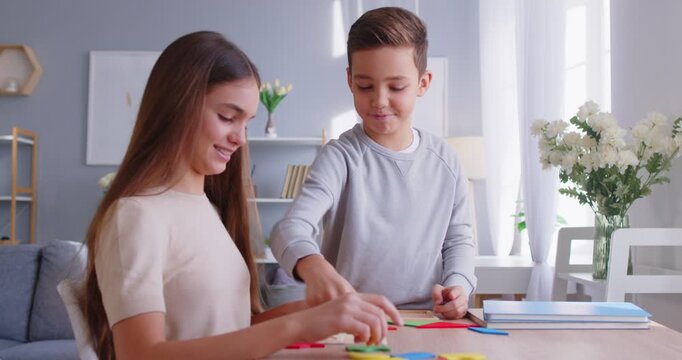 Smiling friendly children game, little daughter, son playing logic strategy wooden board game at table together, family engaged in educational activity at home, developing, learning via amusement 
