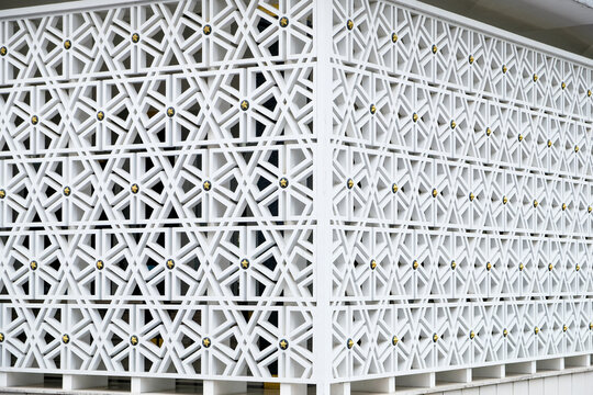 Modern white ventilation roster blocks featuring intricate Islamic geometric patterns with gold star accents on a building wall
