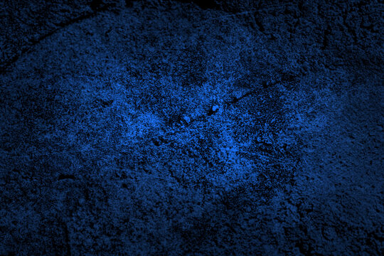 Abstract dark blue concrete or stone wall texture with bright neon light effect in the center and vignette borders