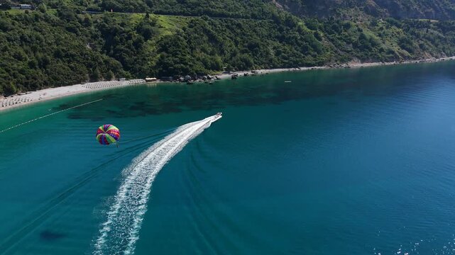 Aerial view of colorful parasailing over a turquoise coastline