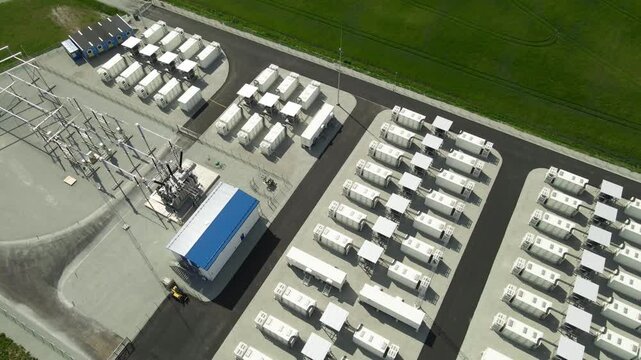 High angle drone view of a large battery energy storage park with containerized BESS units and adjacent substation, showcasing renewable grid infrastructure and stabilization technology