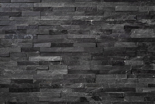 Background of textured natural stone tiles in grey color, modern dark gray slate stone wall cladding texture, elegant grey quartzite brick wall background for contemporary design