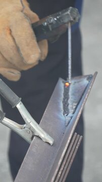 Industrial steel fabrication worker fuses metal beams at a shop facility during a complex welding project. Macro vertical shot.