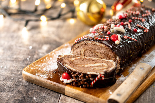 Chocolate Christmas yule log cake on wooden table and christmas decoration