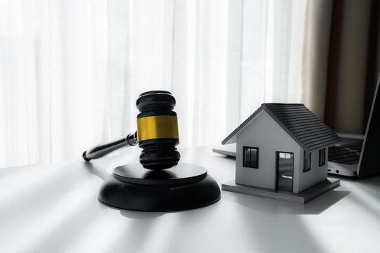 Judge gavel beside a model house and laptop represents real estate law, property auction, mortgage foreclosure, legal disputes, housing contracts and residential property transactions.