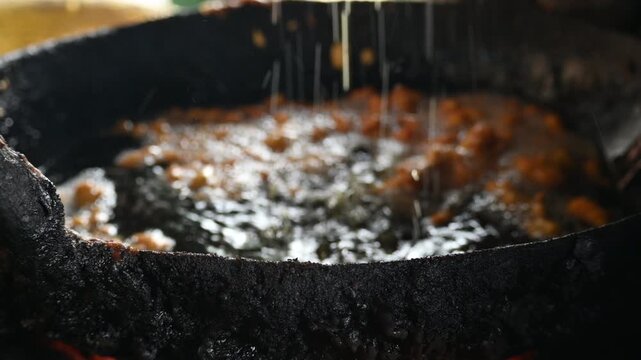 Delicious pakora snack frying deeply in boiling hot oil pan. It is a popular South Asian deep-fried snack made of vegetables, paneer coated in a spiced batter typically composed of gram flour, spices.