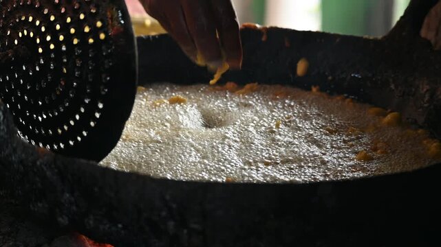 Delicious pakora snack frying deeply in boiling hot oil pan. It is a popular South Asian deep-fried snack made of vegetables, paneer coated in a spiced batter typically composed of gram flour, spices.