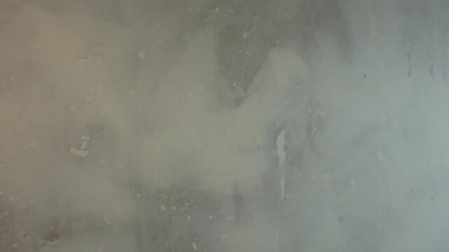 Close up view gliding past a damaged wall during a home renovation project, with remnants of adhesive and old wallpaper creating a textured and weathered abstract background surface