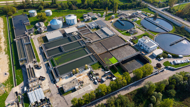 Aerial view of Depuratore di Truccazzano, a wastewater treatment plant featuring circular sedimentation tanks, rectangular aeration basins, and industrial facilities in Truccazzano, Lombardia, Italy.