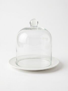 Empty clear glass dome cloche on white ceramic plate isolated on white background, bakery and kitchen