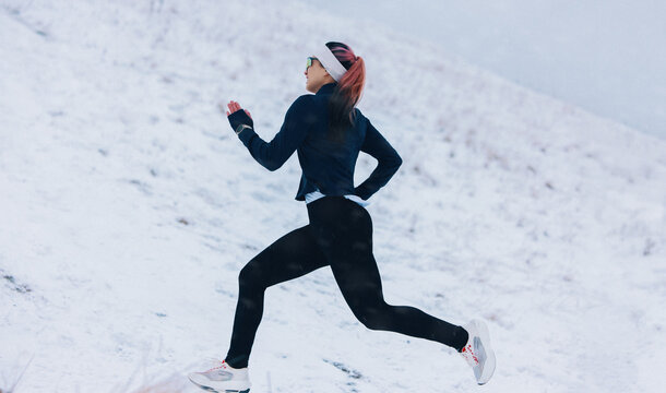 Nature running places the woman on a snowy winter route during fitness training