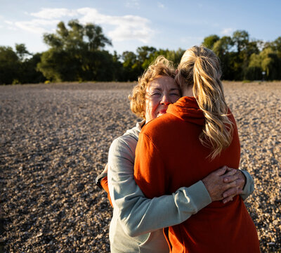A senior mother hugs her young daughter outdoors in nature