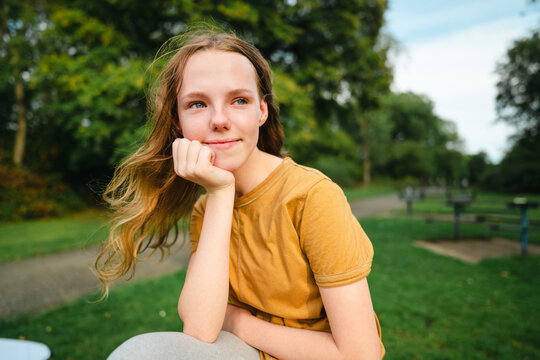 A thoughtful teenage girl relaxes in an urban park