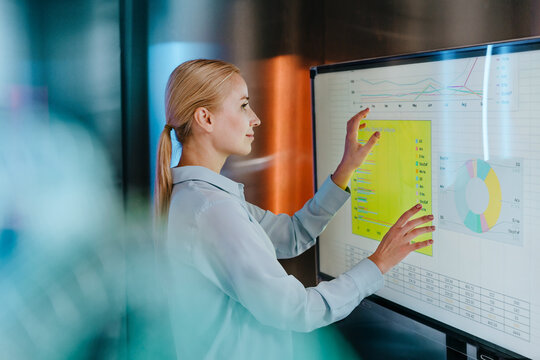 Businesswoman analyzes digital data on a modern touchscreen in office