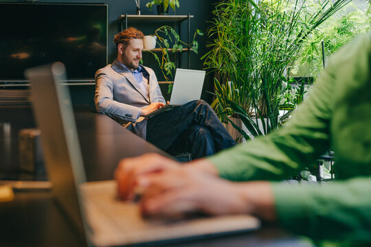 Smiling businessman works on laptop at the green office desk