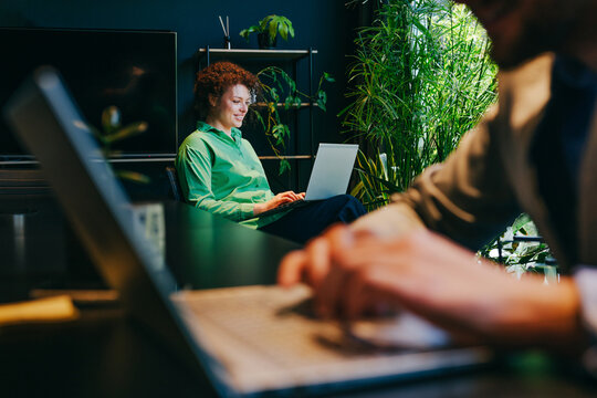 Smiling businesswoman working on laptop in modern green office