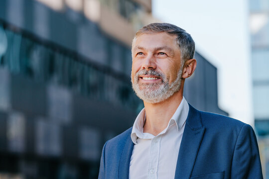 Smiling businessman stands outdoors in the city