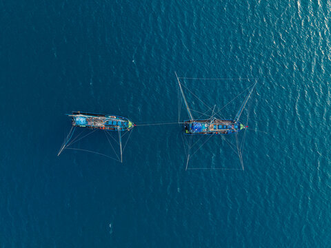 Aerial view of two traditional fishing vessels known as kapal pukat operating in the deep blue waters of the Karimunjawa, Central Java, Indonesia.