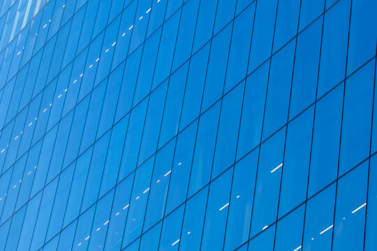 Abstract modern architecture in London England with a blue glass facade geometric lines reflections and windows across an abstract glass facade