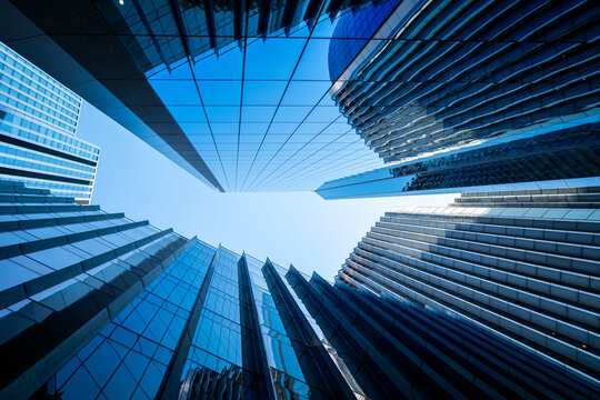 Modern urban architecture in London England from a low angle with glass skyscrapers and converging facades around sky creating perspective