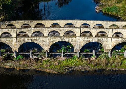 Aerial view of the historic stone bridge at Pakruojis Manor, featuring multiple arches spanning the river in Pakruojis, Siauliu apskritis, Lithuania.