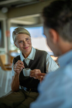 Businesswoman holding coffee cup discusses contract with businessman