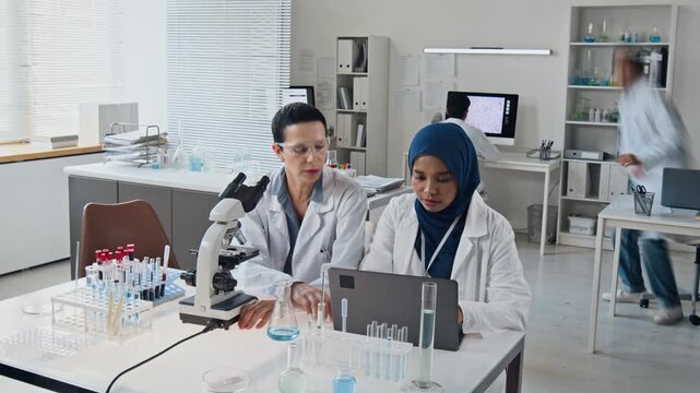 Diverse multiethnic scientists conducting laboratory research using microscope in time lapse. Footage ideal for biotechnology campaigns, pharmaceutical advertising, and medical promo
