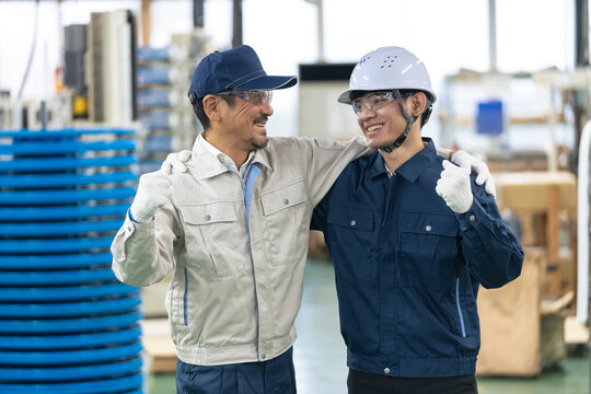 肩を組む工場作業員。製造業、技能実習生、外国人、人材、雇用、求人、産業、やる気、元気、努力、挑戦