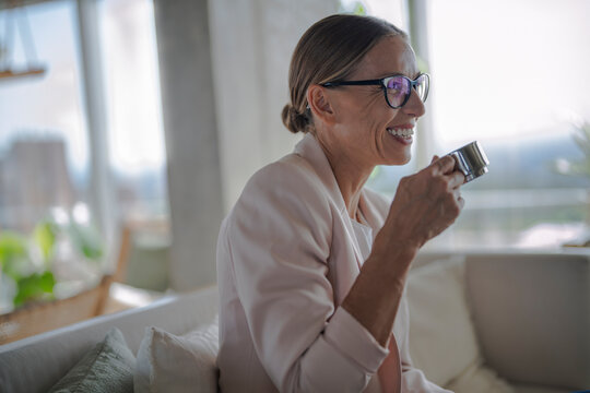 Smiling businesswoman drinks coffee indoors for work life balance