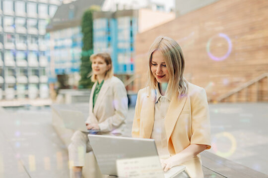 A businesswoman works on a laptop outdoors