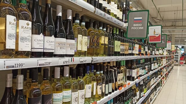 Russia. Moscow. Rows of wine bottles on supermarket shelves. Price tags and signs "Wine of Russia", a long showcase in perspective. Alcoholic beverages department, assortment selection.