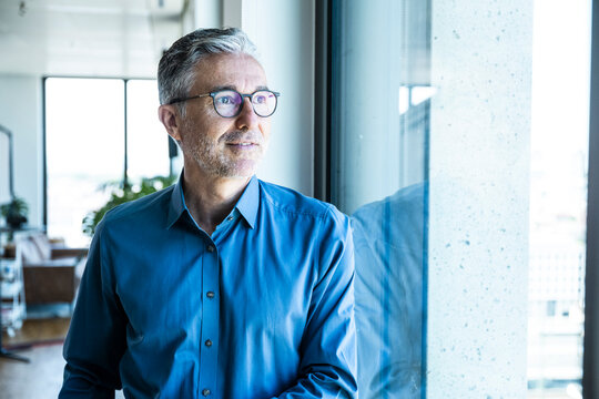 Confident businessman looks out the window in a modern office