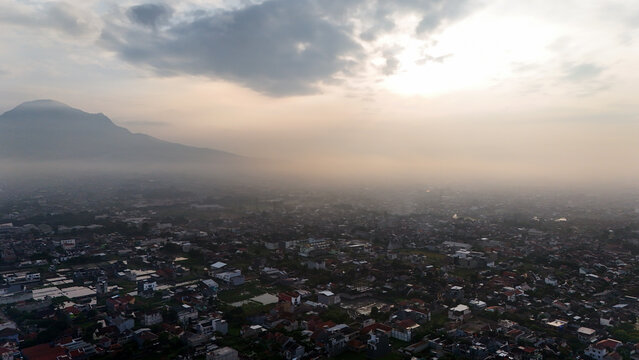 Aerial view of the Gedebage district with dense residential rooftops and a distant mountain under a hazy sky, Bandung, West Java, Indonesia.