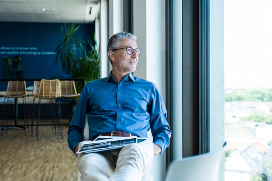 A businessman relaxes by the window in a modern corporate office