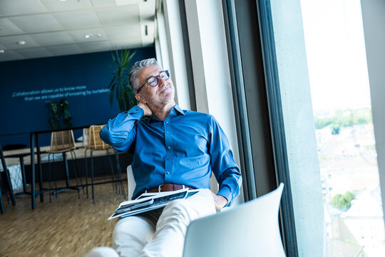Smiling businessman relaxes by the window in a modern office