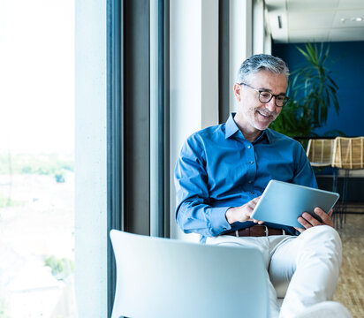 Smiling businessman uses a tablet in the office