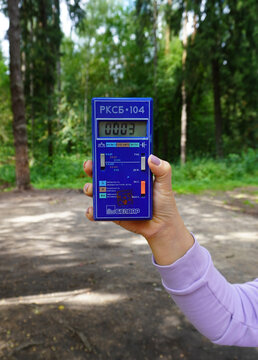 07.07.25. Russia.Moscow. Vertical image of a man holding an RKSB-104 dosimeter in a forest, a radiation detection device used to measure the state of the environment and monitor nuclear safety