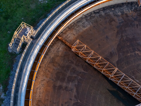 Aerial view of wastewater treatment clarifier tank with circular concrete walls and a metal bridge structure in Monroe, Michigan, United States.