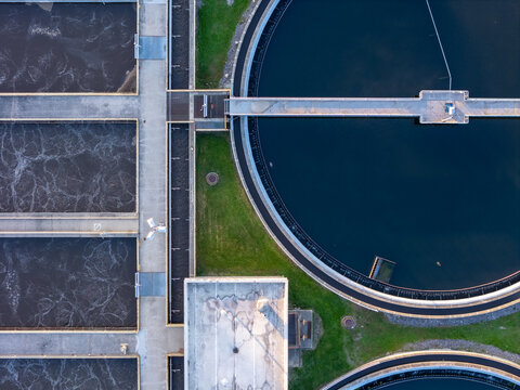 Aerial view of the Bedford Waste Water Treatment facility, featuring large circular clarifier tanks and rectangular aeration basins with concrete walkways in Monroe, Michigan, United States.