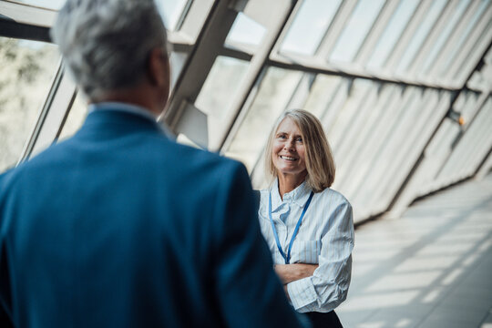 A smiling businesswoman talks to a businessman at a trade fair